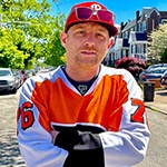 Full Sail Film Production MFA grad Panda Lord in an orange hockey jersey on a residential Philadelphia street.