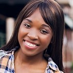 Brandie Green smiles at the camera. She is standing outdoors and wearing a flannel button-down shirt.