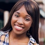 Brandie Green smiles at the camera. She is standing outdoors and wearing a flannel button-down shirt.