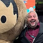 Adam Cipoletti stands with his arm around Astro Nomical, one of Salesforce’s mascots, at the Dreamforce conference.