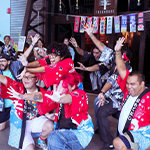 A crowd of students pose for the camera in front of the Treehouse wearing colorful traditional Japanese clothing.