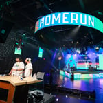 A wide shot of Full Sail’s esports arena during the Sunburst Classic with the words “home run” in large block lettering on an LED screen.
