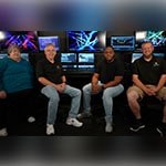 Four people sitting in front of a Grand MA lighting console at Full Sail University.