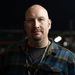 Headshot of Andrew Garraway wearing a blue and grey plaid flannel and a Full Sail lanyard, complete with Full Sail pins.