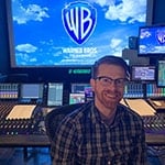 Recording Arts grad Ryan Kennedy sits in front of a large recording console.