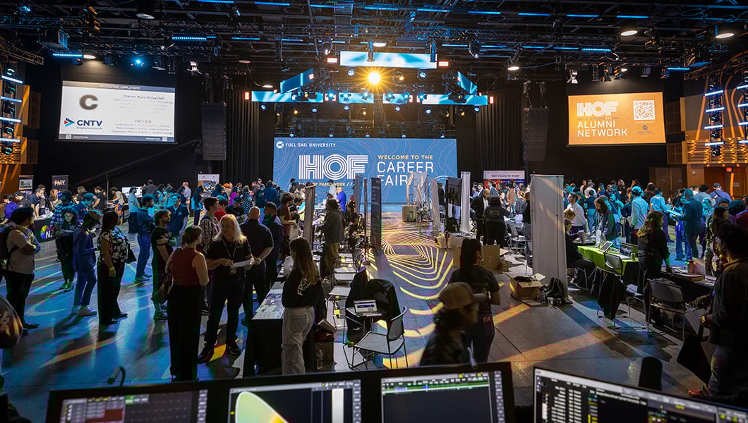 Full Sail students and alumni gather at the Career Fair where various companies have set up booths and talk to attendees.