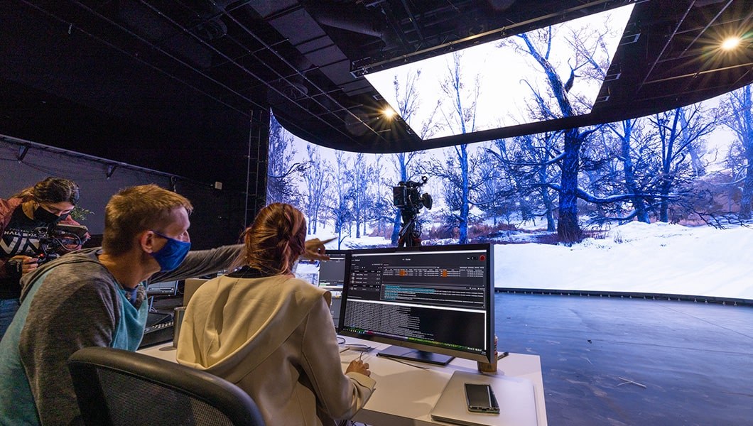 Crew members use Unreal Engine to work on a floor-to-ceiling virtual production screen.