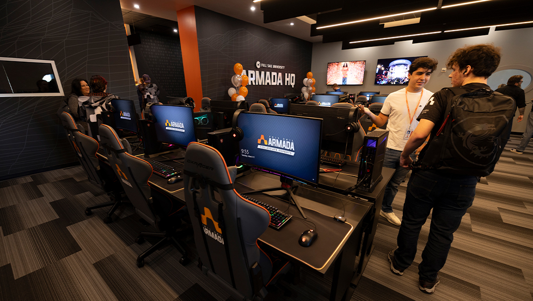 A wide shot of the front room of Armada HQ featuring high-end gaming PCs, branded chairs, and students.