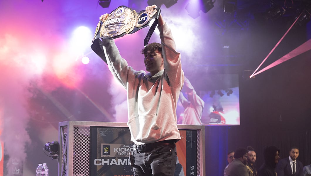 Victorious player, Fancy, is seen holding up the championship belt in celebration, surrounded by vibrant stage lighting and MCS commentators in the background.