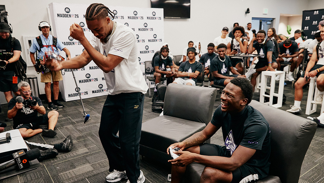 A lively ‘Madden’ NFL gaming event with players laughing and celebrating while surrounded by an enthusiastic crowd.