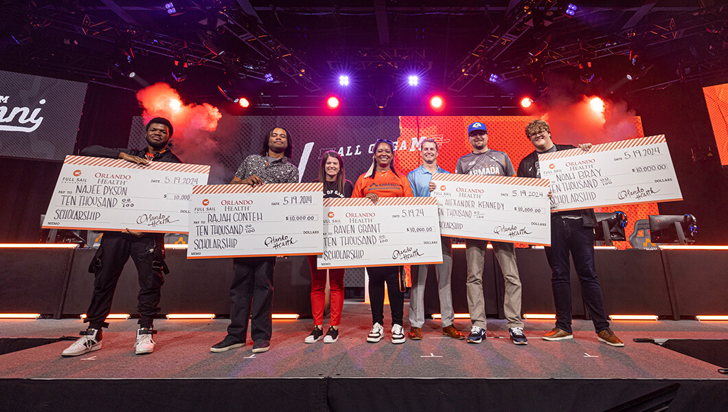 Students and staff on stage while holding oversized checks with Full Sail scholarships.