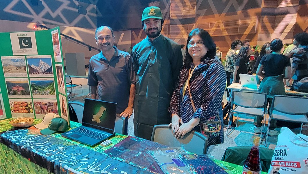A group of three people standing behind a table representing Pakistan at a cultural festival.