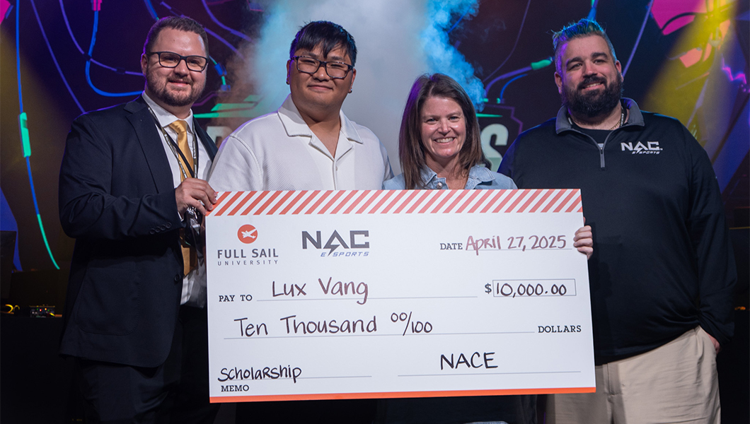 Lux Vang stands next to three Full Sail and NACE staff. They are holding a giant check for $10,000.