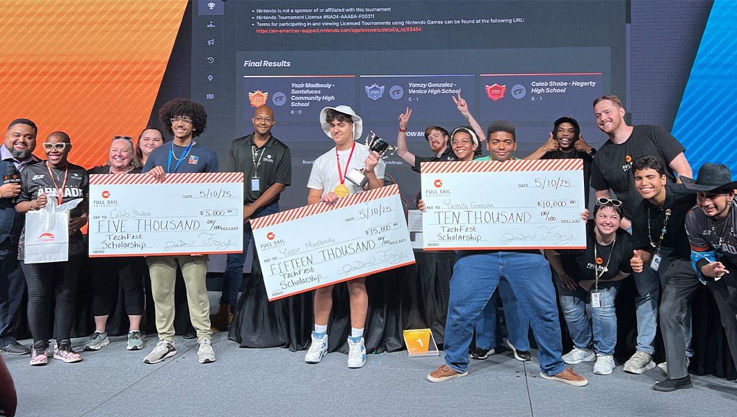 Caleb Shobe, Yazir Madbouly, and Yamzy Gonzalez stand onstage holding giant checks. Students and staff members stand around them.