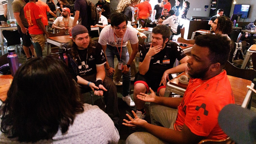 A group of people in Armada apparel chatting while seated at a table in the Treehouse.