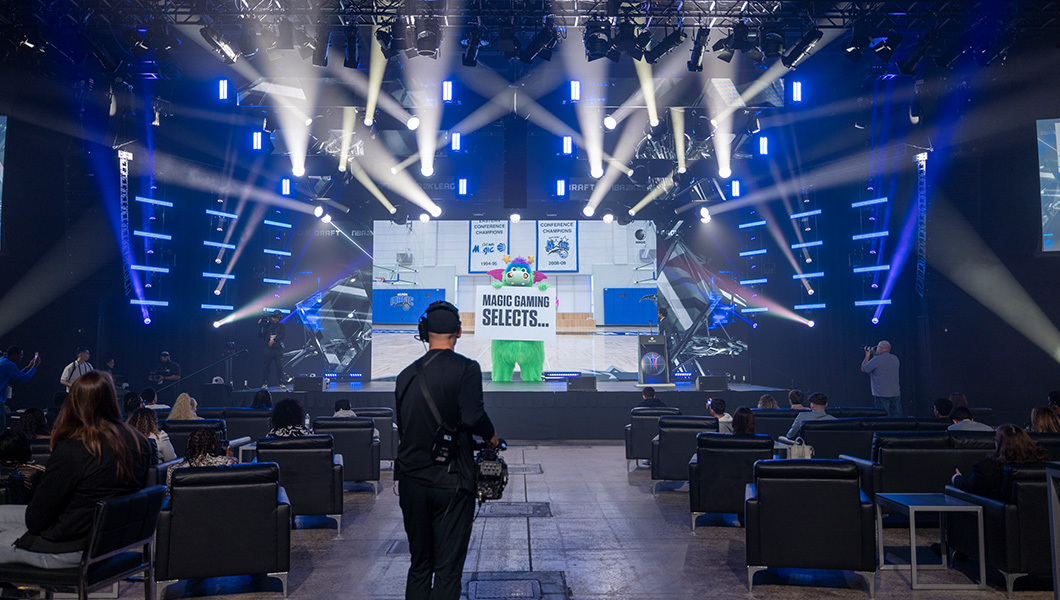 Orlando Magic mascot Stuff appears on a large screen on stage while holding a sign that reads “Magic Gaming Selects.”