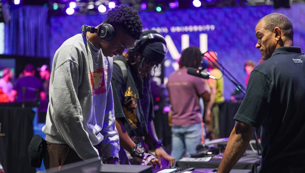 Two students are trying out sound engineering equipment at the Tech Expo. They are both wearing headphones.