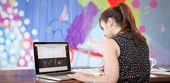 A student in a polka square top studies the analytics of a global infographic.