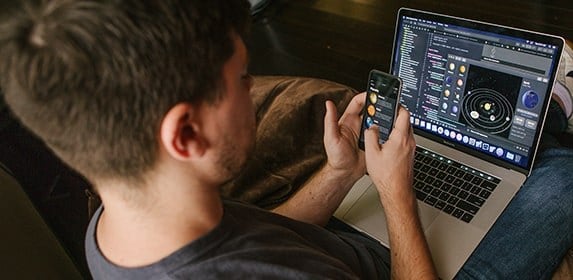 A student compares the visual layout of their astronomy app on a smartphone compared with a MacBook Pro.