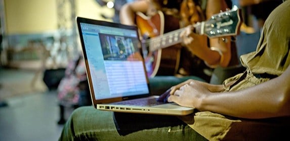 A student records a musician playing an acoustic guitar.