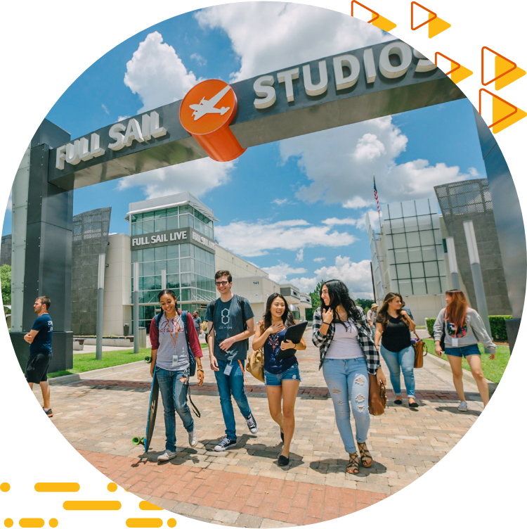 Four students casually chatting and walking under the Full Sail Studios archway, a blue sky with clouds in the background.