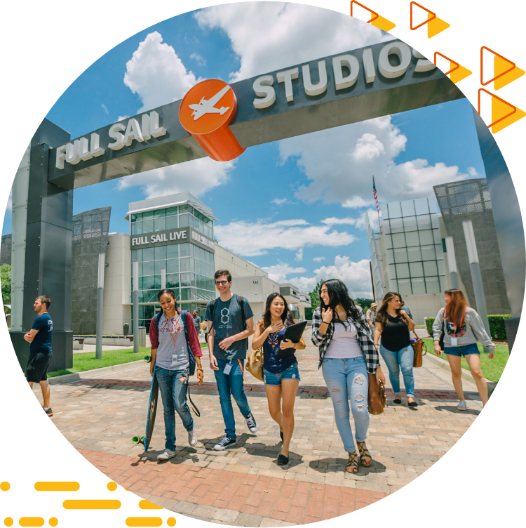 Four students casually chatting and walking under the Full Sail Studios archway, a blue sky with clouds in the background.